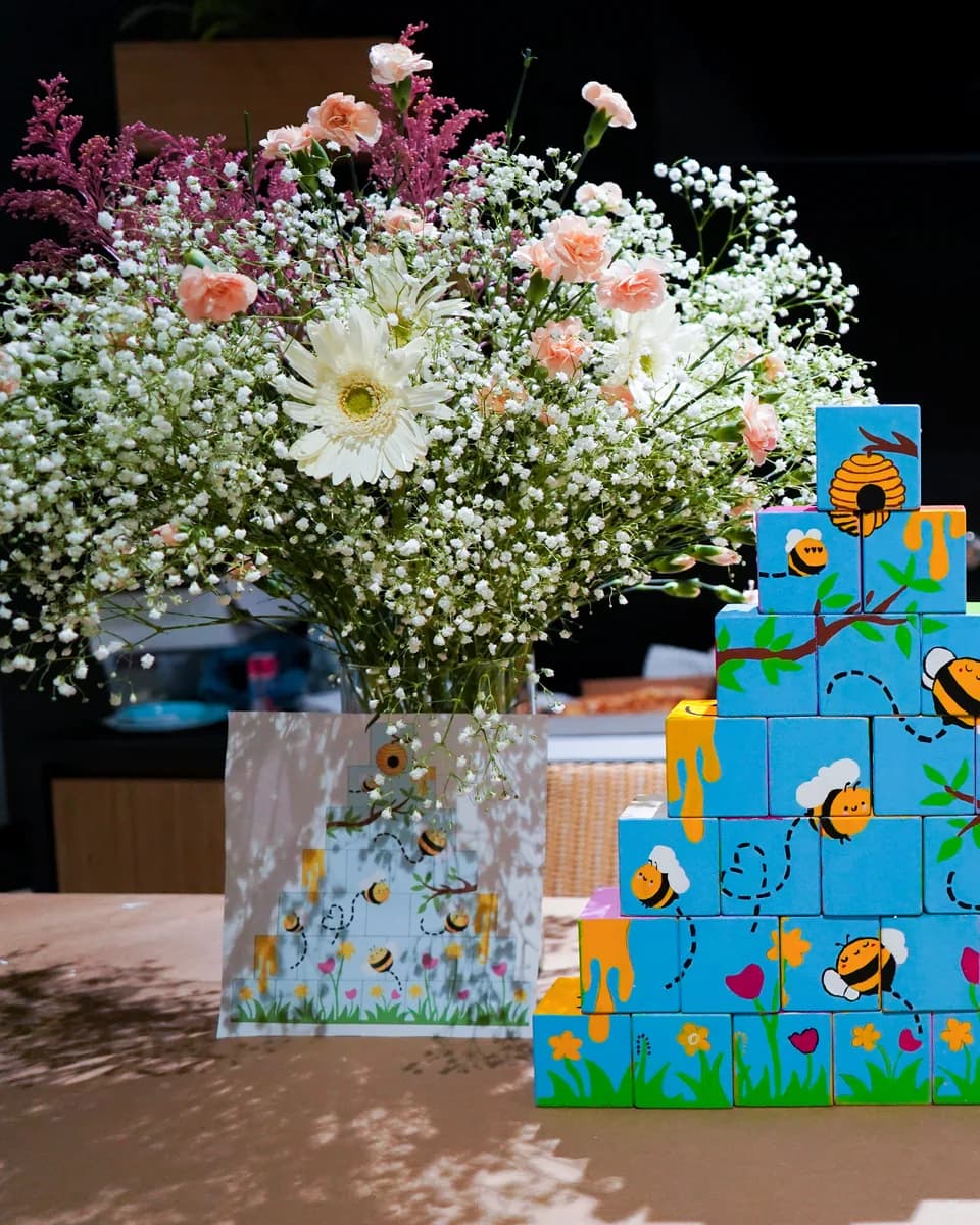 Collective mural of painted cubes with bees and flowers, assembled at a baby shower