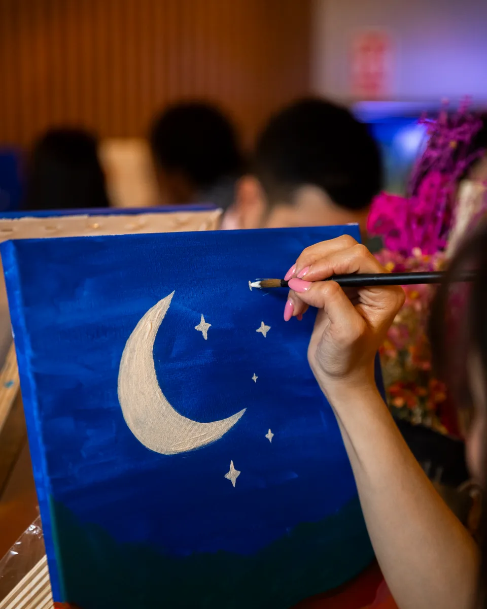 Canvas of a moon with stars over mountains, painted step by step at a Paint Night