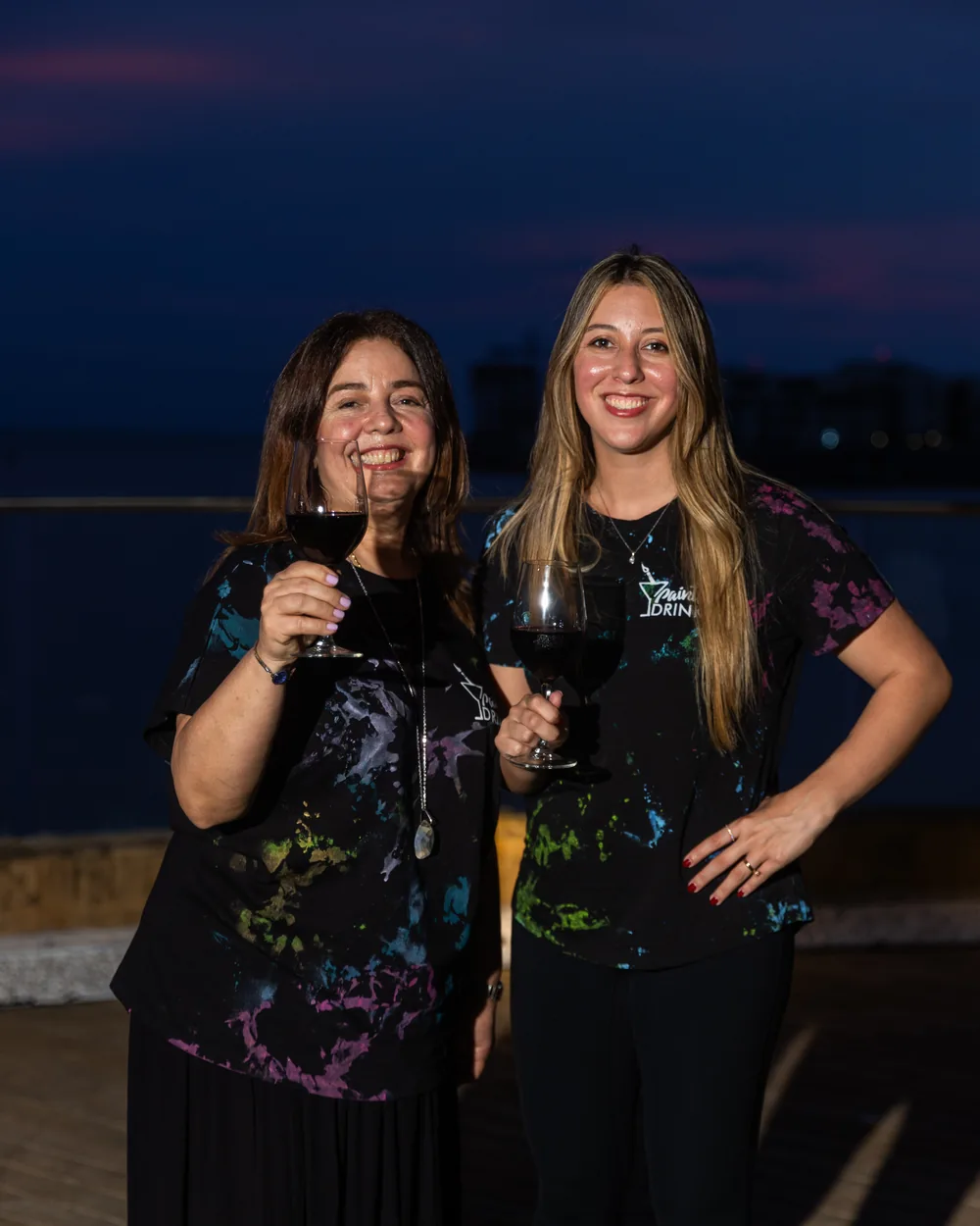 Irgia Barros and Jessica Vaca, mother and daughter founders of Paints & Drinks, toasting at sunset during the 9th anniversary celebration