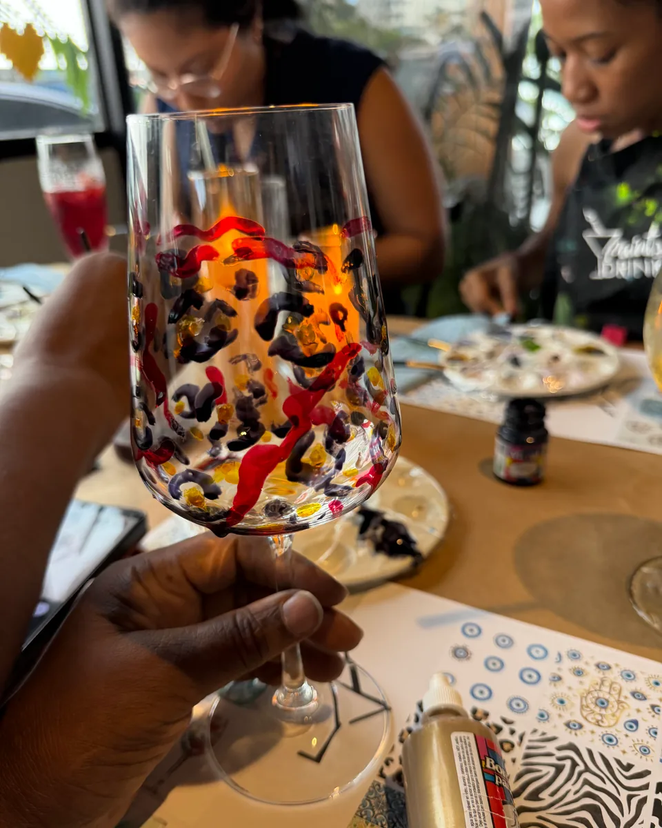 Wine glass hand-painted with red, black and gold strokes at a Paint Your Glass session