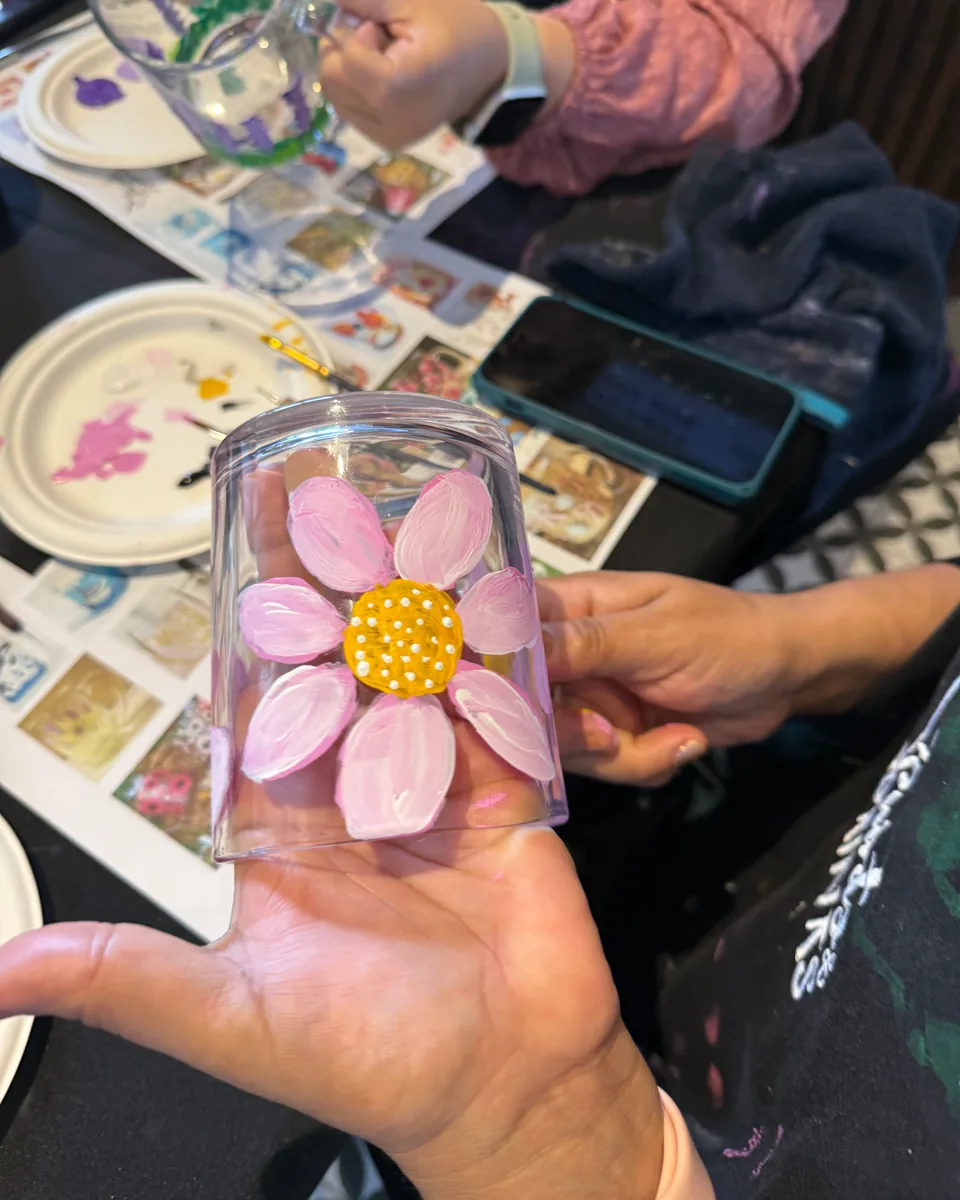 Glass mug hand-painted with a pink flower at a Paint Your Mug session