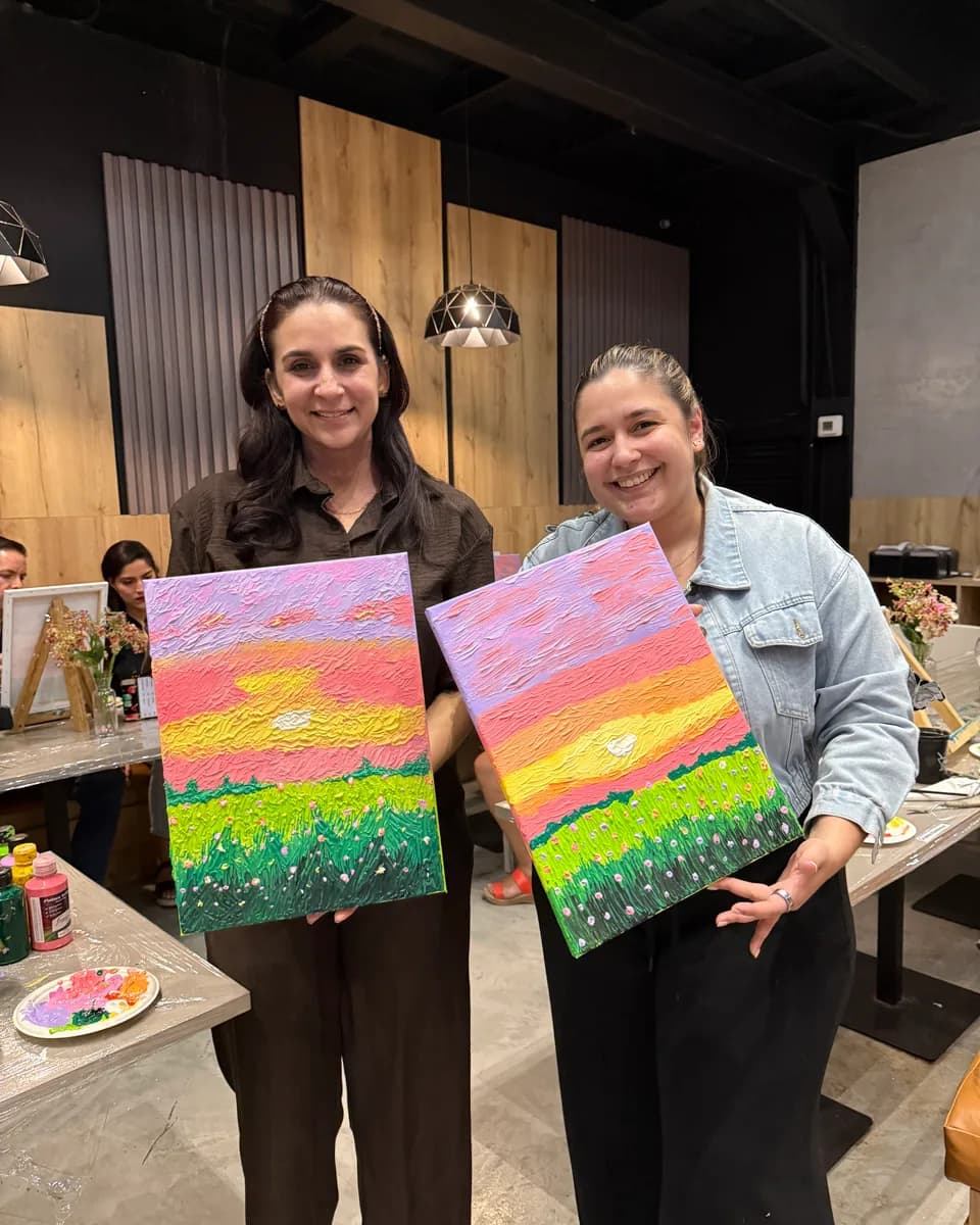 Dos participantes muestran sus atardeceres en relieve creados en una noche de Pintura con Textura